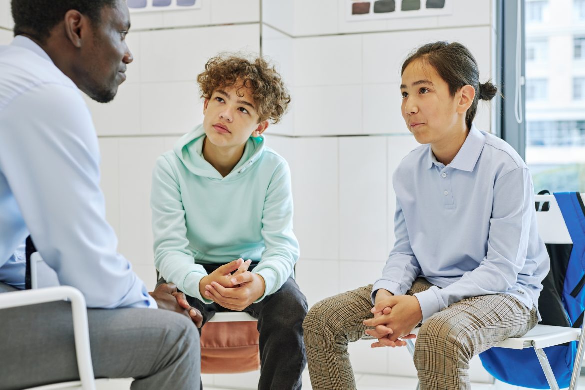 Portrait of two teen boys listening to counselor in school therapy session