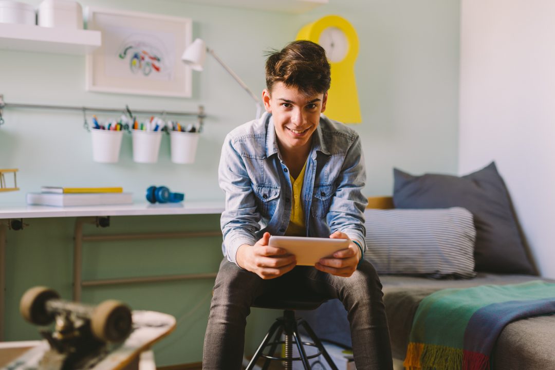 He is always on line with his school mates.Teenage boy using tablet in his room.